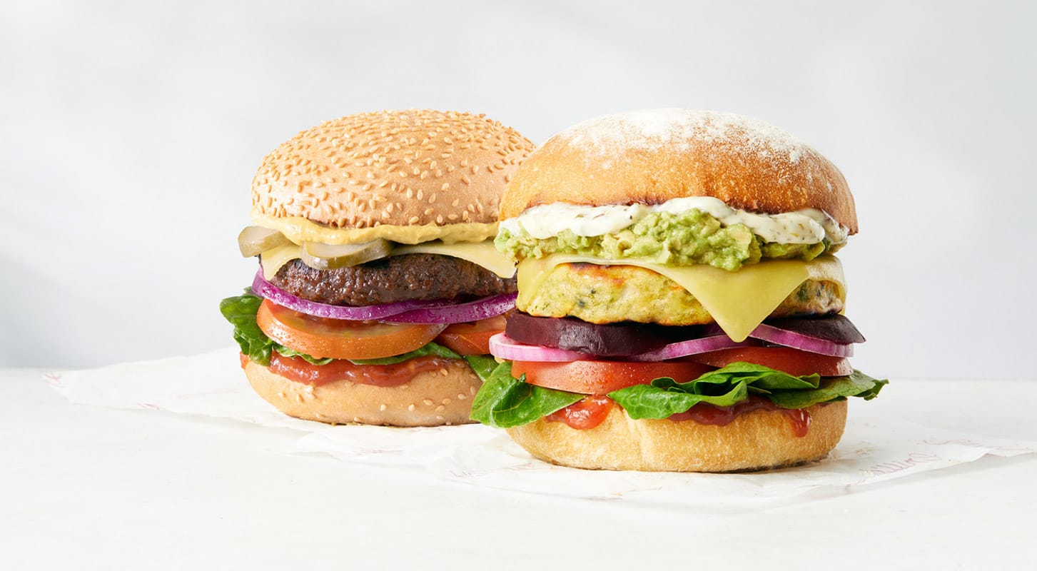 A close-up of two delicious cheeseburgers on a table, featuring fresh toppings and toasted buns.